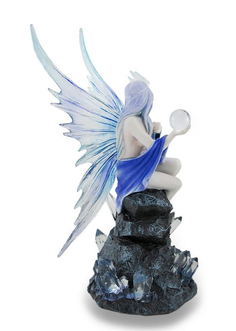 Back view of fairy in blue sitting on crystal rock