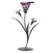 A tealight candle holder made to look like a deep purple lily flower with two smaller blossoms, on a metal stalk with leaves.