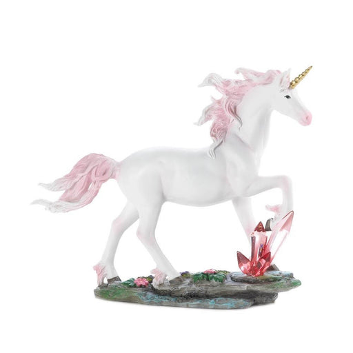White unicorn figurine with pink mane and tail and a golden horn walks across stone with flowers and pink transparent crystals