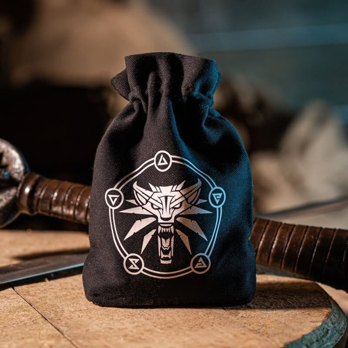 Witcher dice bag shown on a table with weaponry