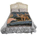 Tapestry blanket showing two wolves standing in the sunset, in a winter mountain landscape. Shown draped over a bed