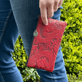 Red Cloud Dragon zip leather wristlet pouch, shown held by someone wearing jeans