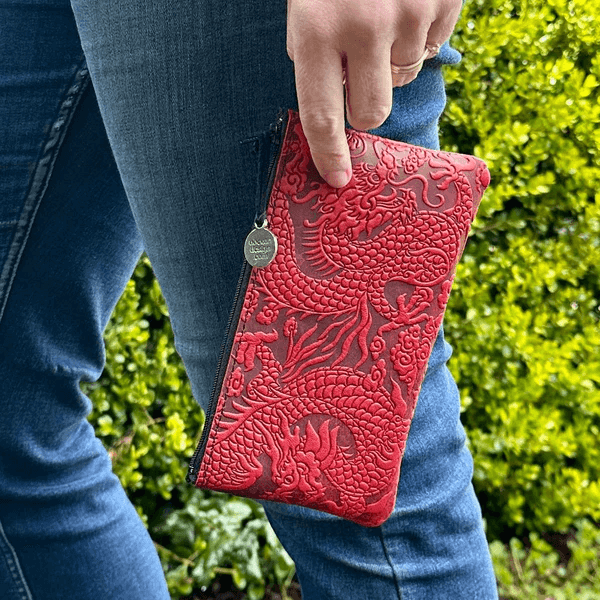 Red Cloud Dragon zip leather wristlet pouch, shown held by someone wearing jeans