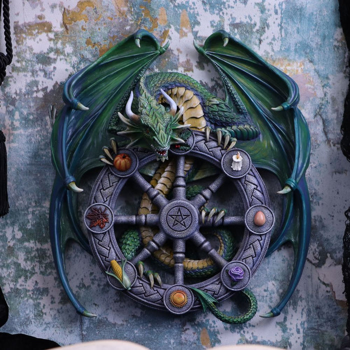 Wheel of the year dragon plaque shown displayed on a rustic wall